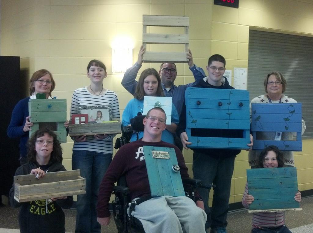 Left to right: Junior Anna Solberg, senior Mason Rumpf, senior Katie Regan, Diane Nelson, senior Chloe Keeney, junior Paige Grave, Heath Pattschull, senior Travis Krugler and Teresa Lori display the programs art pieces. The  goal of the program is for students to be able to become independent in the working environment.