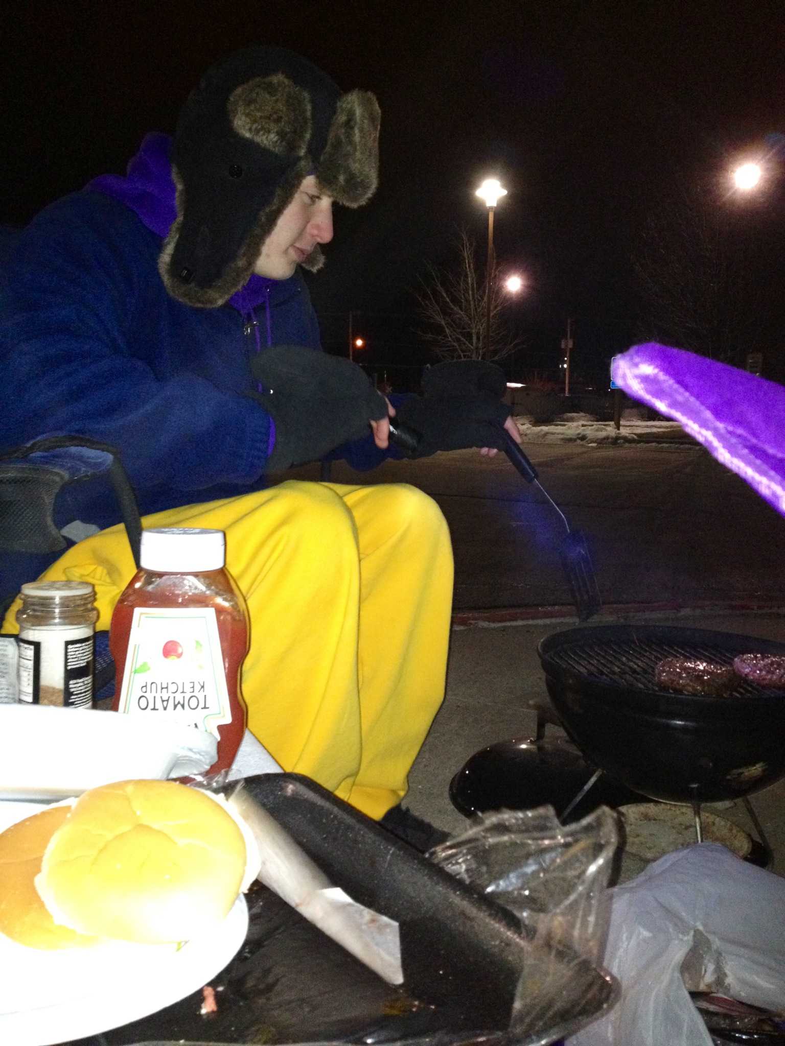 Freshman Seth Schieffer trys to stay warm by cooking hamburgers and hotdogs outside of the Marshalltown YMCA at the boys state swimming campout. 