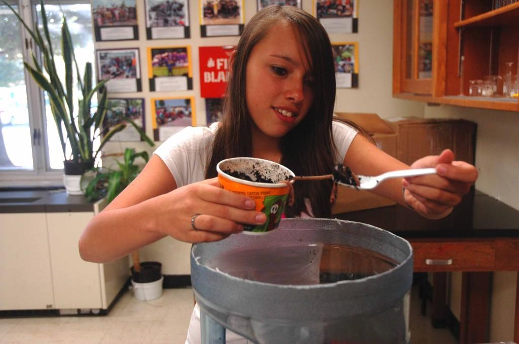 Sophomore Alexis Forest scoops worms into her groups eco bottle for one of their environments.  Each group of students was required to build their own eco bottle with different environments. 