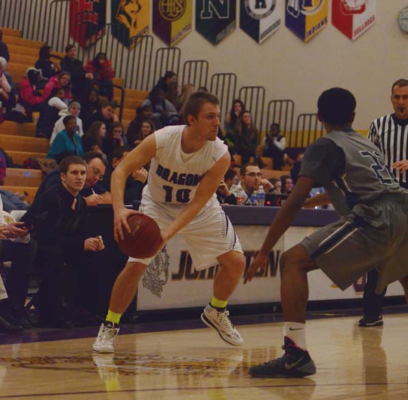 Senior Nick Stitzell looks to pass the ball while being guarded by a Roughrider defender in a prior game. The game was played Feb. 11 and the Dragons won with a score of 59-53.