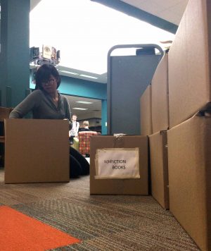 Alena Pham '17 sorts the books that will be going to the auction during her service credit time. Pham helps librarian Ruth Thoreson every day by quickly working on the books that are left on the "Discarded Books" cart and packing them into the boxes corresponding with the genre of writing.