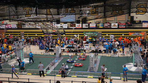 Six teams assemble on the field to compete in a match at the CowTown ThrowDown Robotics event. These teams come from four states and may compete with each other at other events during the year.