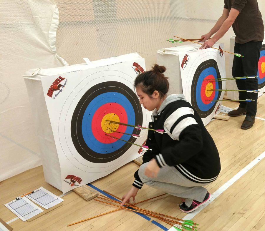 Archer Vivan Nyugan '19 picking up the arrows she pulled from her target. She had two arrows in the yellow even with this being her first tournament.