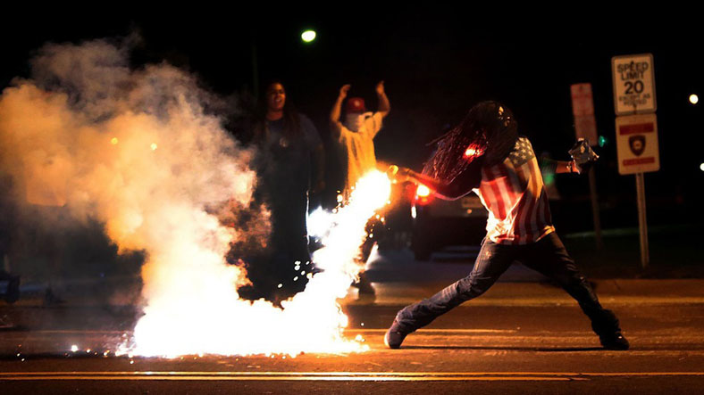 This photo has become iconic as the official photograph of the Ferguson protests, showing a man throwing a tear gas container away from the protesters near him.