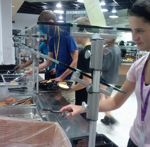 On Sept.10, junior Aubrey Sesker uses tongs to reach for a whole wheat bun for her chicken fillet sandwich during B lunch. Chicken fillet sandwiches are among the favorite entrees that are provided at school lunch. 