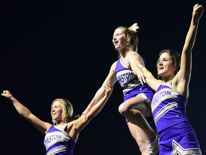 Juniors Sage Hassel, Sophia Cresta, and sophomore Kati Anderson create a pyramid to start a cheer with the crowd. The homecoming varsity football game was held Sept. 26 against the North Polar Bears. The Dragons won 45-6.