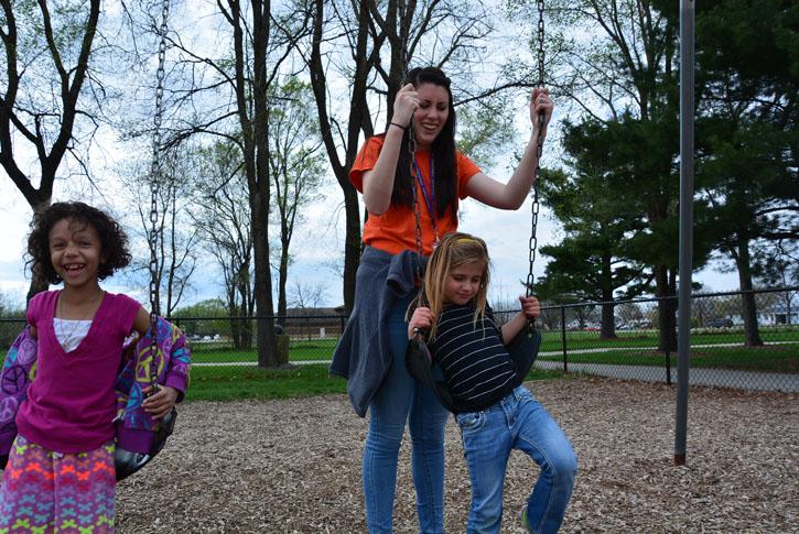 Senior Sam Wilkinson pushes two girls on the swings at the Lawson Elementary School playground during her shift at Kids/Teen Connection (KTC). Wilkinson has been working at KTC since September 2014 and thoroughly enjoys building relationships with the kids she works with. 