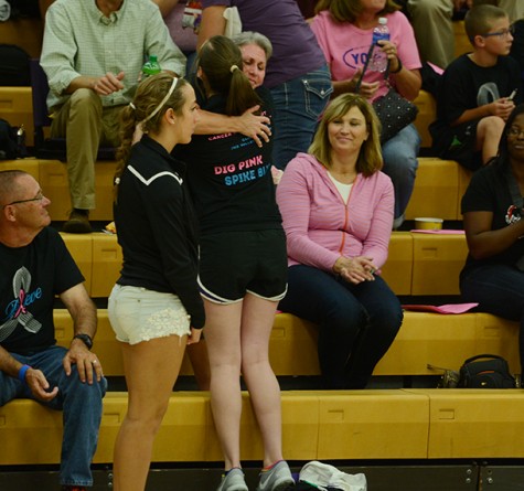 Junior Anna Miller hugs and hands a carnation to one of the standing cancer survivors in the crowd. The girls' varsity volleyball game took down the Urbandale Jayhawks during the Digpink/ Spikeblue game Sept. 29.