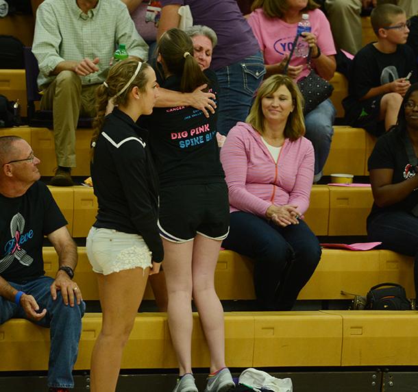 Junior Anna Miller hugs and hands a carnation to one of the standing cancer survivors in the crowd. The girls varsity volleyball game took down the Urbandale Jayhawks during the Digpink/ Spikeblue game Sept. 29. 