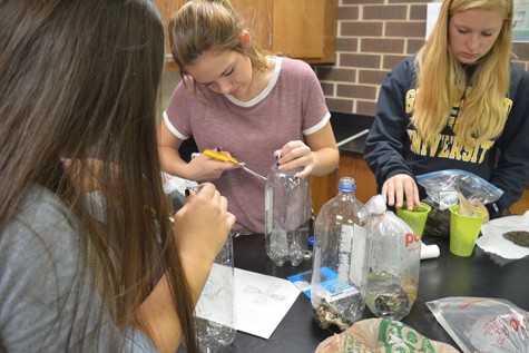 Sophomores Jordan Durst, Sydney Hughes and Melinda Nguyen cut open their bottles to place the dirt and rocks inside. Their next observation is Oct. 28, and the observations will continue weekly until Nov. 23.