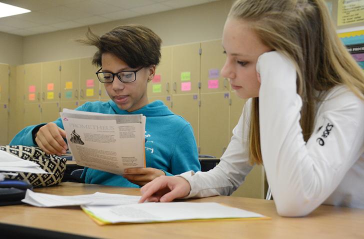 Helping ----- as she continues a writing assignment, junior Leah Denny aids in tackling the paper. Denny and ---- began the work soon after a presentation from a foreign exchange student earlier in the afternoon.