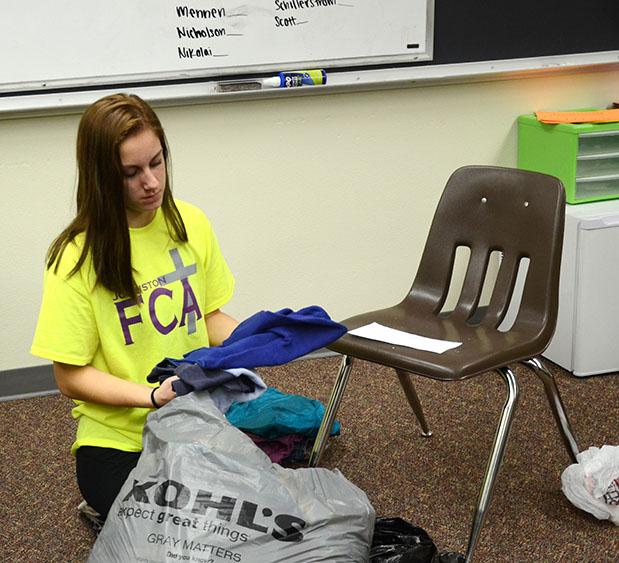 Junior Anne Krone folds clothes that were donated to the drive. The students that helped fold the clothes tallied up the amount of clothes each room donated to select the winner.
