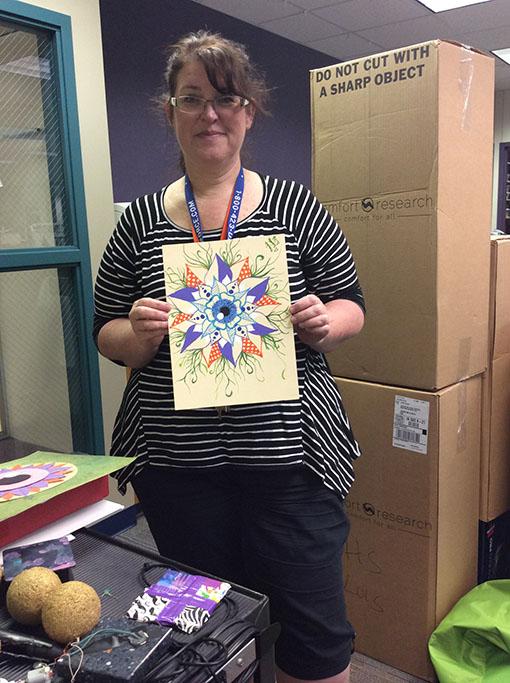 Librarian Ruth Thoreson holds up a piece of art work created by senior Analea Couture using the Maker Space. The Maker Space is an area in the back of the library where students can go and be creative.