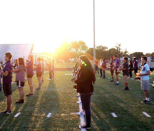 The sun rises over the marching band as they prepare to march.
