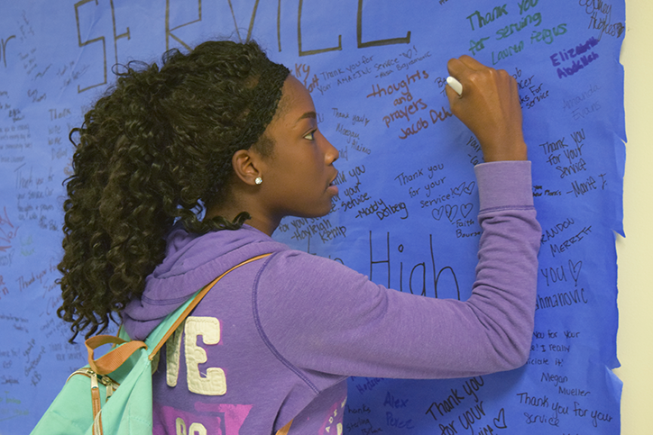 Kennedria Jackson 19 signs one of the posters for fallen officers Justin Martin and Tony Beminio. The posters will be sent to the Des Moines and Urbandale police stations.