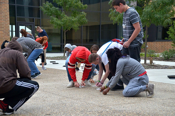 Students hunt for beans on the ground in one of the courtyards. Students recorded the amount of beans they had collected after the trial.