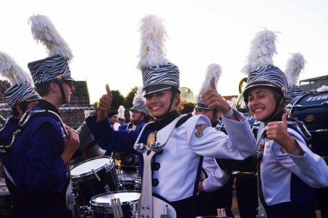 Cari Naanep '19 (left) and Beth Giles '19 (right) wait for their turn to run onto the stadium field. Both are part of drumline and play snare drums.