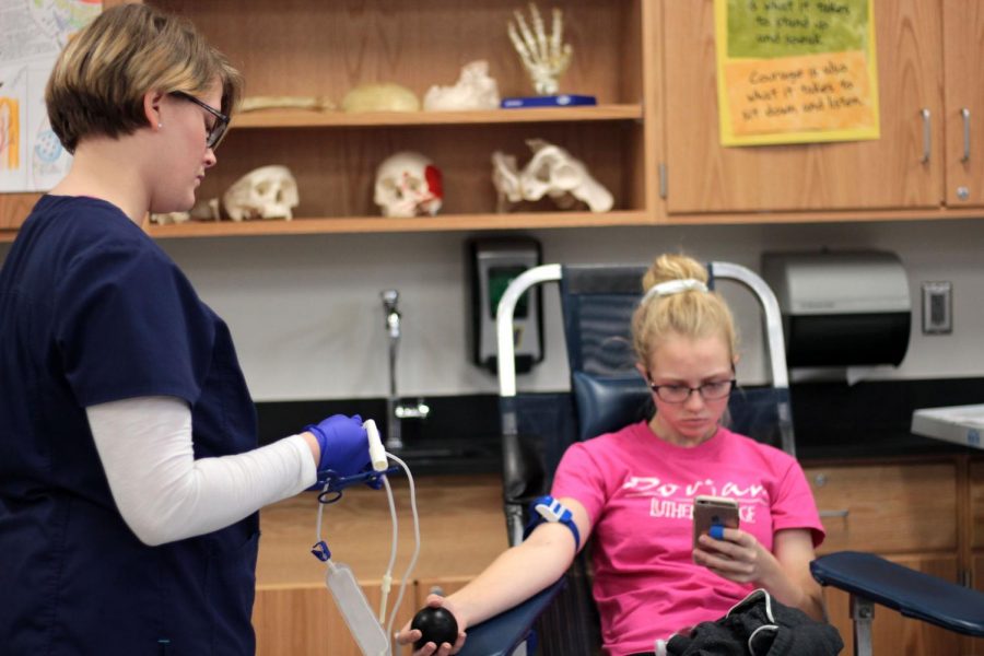 Hailey Abbey 18 checks her phone as she donates whole blood cell. The blood drive took place on Nov. 8 in room 123.