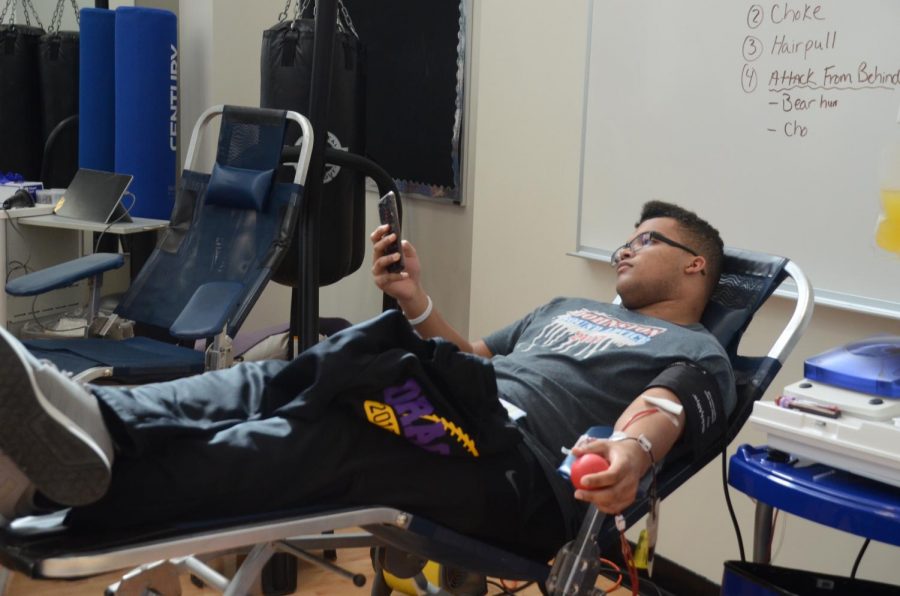 Marshawn Gunn 20 plays on his phone while he give blood. 