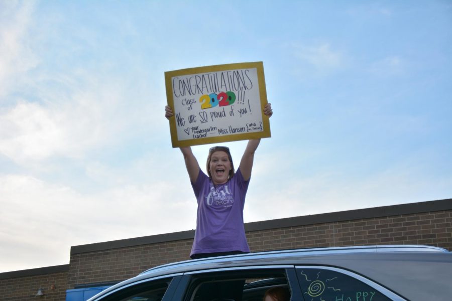 Former Wallace teacher holding a sign out of her car for the passing graduates.