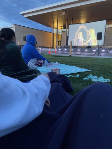 A picture of the movie green and students watching the Disney movie Tangled at the Town Center.